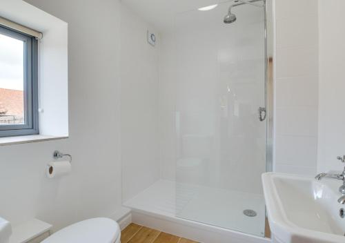 a white bathroom with a shower and a sink at The Hayloft in Tatterford