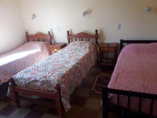 a bedroom with two beds and a table with a bedskirts at La Primavera in San Salvador de Jujuy