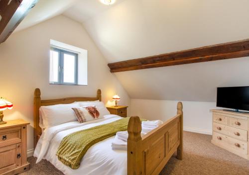 a bedroom with a wooden bed and a tv at The Hayloft in Tatterford