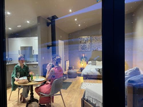 two women sitting at a table in a room at Quirky, Luxury Hideaway in Llanbrynmair