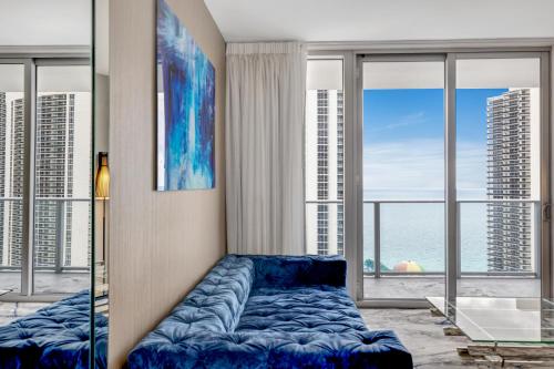 a living room with a blue couch in front of windows at HYDE HOUSE - Luxury Waterfront 2BR 2BA Apartment Suite with direct ocean view, roof top pool, resort amenities in Hollywood