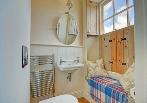a bathroom with a sink and a toilet and a mirror at The Old Bakery in Blakeney