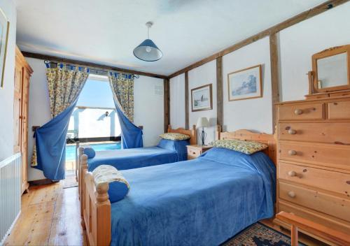 two blue beds in a bedroom with a window at The Old Coach House in Cawston