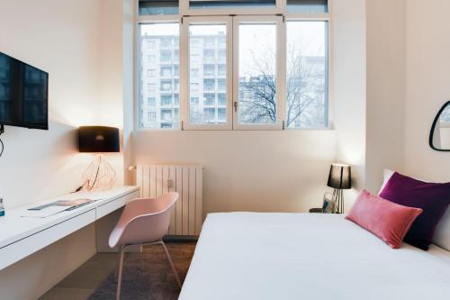 een slaapkamer met een wit bed, een bureau en een raam bij Sweet Inn - Porta Romana in Milaan