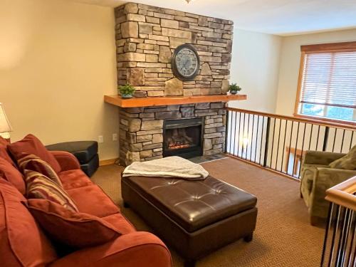 a living room with a stone fireplace with a couch and chair at Pinnacle Ridge Condos by Fernie Central Reservations in Fernie