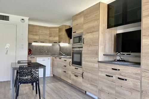 une cuisine avec des placards en bois, une table et une télévision dans l'établissement Nice studio with balcony located in Fréjus, à Fréjus
