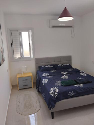 um quarto com uma cama com um edredão azul e uma janela em פטל em Bersebá