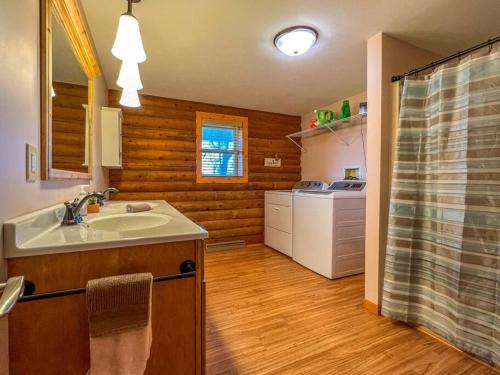 a bathroom with a sink and a kitchen with wooden walls at Elkhorn 3 Bedroom 2 Bathroom Log Cabin Sleeps 8 - Lincoln Log Cabin in Elkhorn