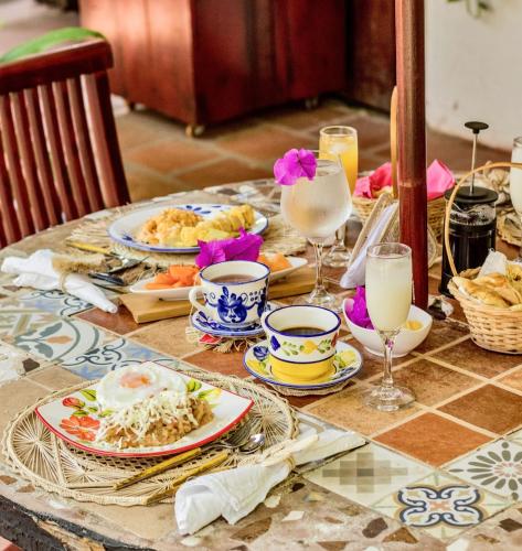 a table with plates of food and glasses of milk at Hotel Boutique Casa de Los Santos Reyes Valledupar in Valledupar