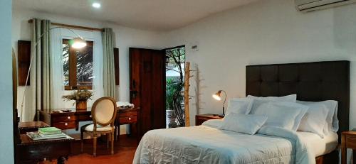 a bedroom with a large bed and a desk and a chair at Hotel Boutique Casa de Los Santos Reyes Valledupar in Valledupar