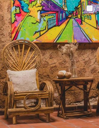 a room with a chair and a table with a painting at Hotel Boutique Casa de Los Santos Reyes Valledupar in Valledupar
