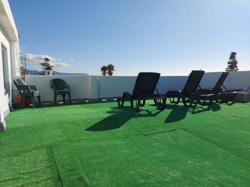 a group of chairs sitting on a patio with green grass at Loft Escobar in Nerja