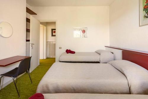 a room with two beds and a table and a chair at Oasi di Mastarone - Il vino e le Rose in Momperone