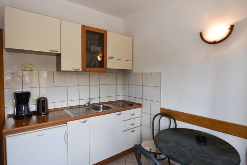una piccola cucina con armadi bianchi e lavandino di Apartments Karmen a Primošten