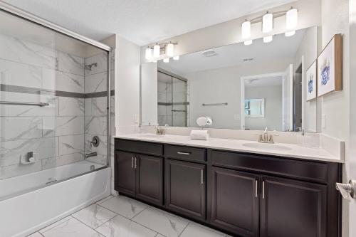 uma casa de banho com um lavatório, um chuveiro e uma banheira em Luxury Decor 5 BR townhome with pool SL4928 em Kissimmee