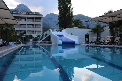a swimming pool with a slide in front of a hotel at Hotel Gold Stone in Beldibi