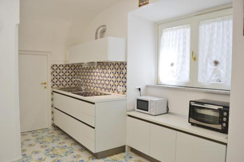 una cucina con armadietti bianchi e forno a microonde di Casa Bianca Amalfi ad Amalfi