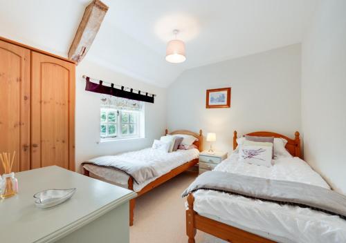 a bedroom with two beds and a table at Watts Cottage in Upton