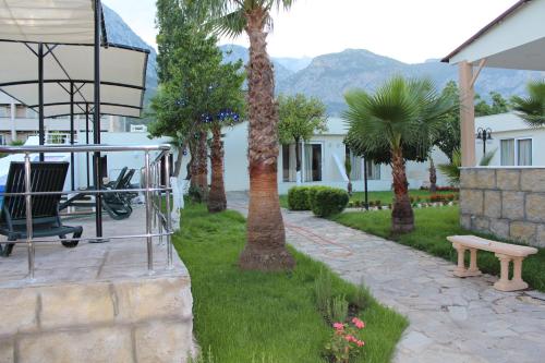 a park with a bench and palm trees and a building at Hotel Gold Stone in Beldibi