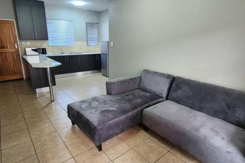 sala de estar con sofá y cocina en Apartment Near Amajuba Mall, en Newcastle