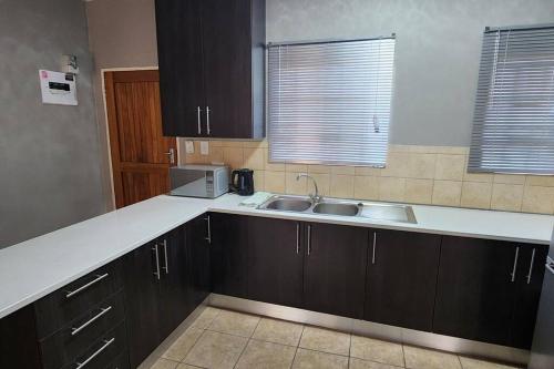 a kitchen with black cabinets and a sink at Apartment Near Amajuba Mall in Newcastle