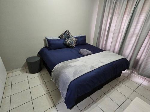 Una cama con sábanas azules y almohadas en un dormitorio en Apartment Near Amajuba Mall en Newcastle
