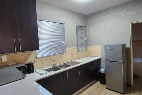 a kitchen with a sink and a refrigerator at Apartment Near Amajuba Mall in Newcastle