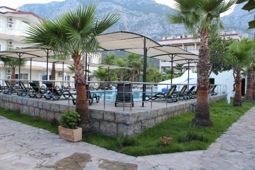 a resort with a pool and palm trees and chairs at Hotel Gold Stone in Beldibi