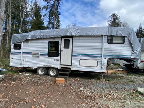 a white trailer with a tarp on top of it at Comfortable RV in a farm in Nanoose Bay