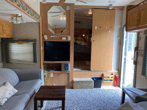 een woonkamer met een bank en een tv in een caravan bij Comfortable RV in a farm in Nanoose Bay