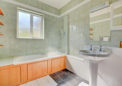 a bathroom with a sink and a bath tub and a sink at Whelk Holme in Cromer