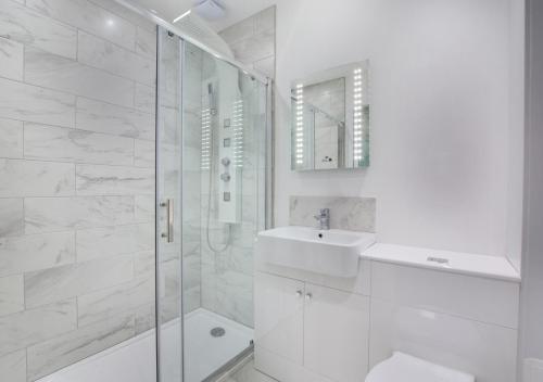 a white bathroom with a sink and a shower at The Retreat in Holt