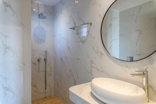 a white bathroom with a sink and a mirror at Blueisla Sea View Suite A in Mikonos