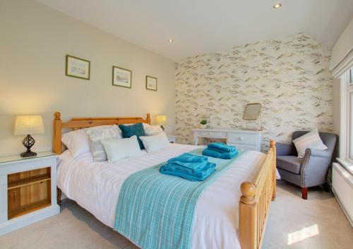 sypialnia z dużym łóżkiem i krzesłem w obiekcie Wren Cottage w mieście Aylsham