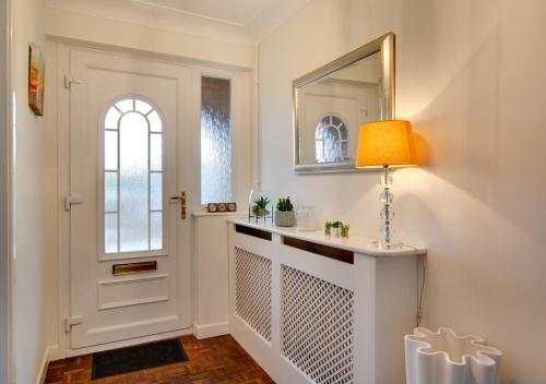 a hallway with a door and a lamp and a mirror at Wyatt House in Norwich