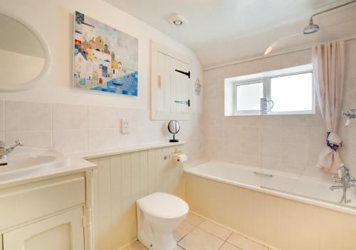 a bathroom with a tub and a toilet and a sink at Thimble Cottage in Dersingham