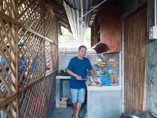 a man standing in a kitchen preparing food at ANNI'S BEACH HOUSE in Lucena