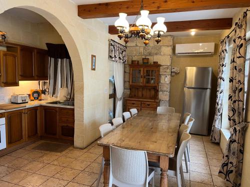 a kitchen with a wooden table and white chairs at Villa Serenita in Xagħra
