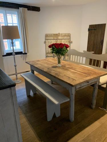 a wooden table with a vase of flowers on it at Lovely Two Bedroom Town House - Minimum 2 Night Stay in Midhurst