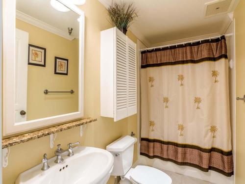 Un baño con lavabo, inodoro y espejo. en Emerald Isle #1007, en Pensacola Beach