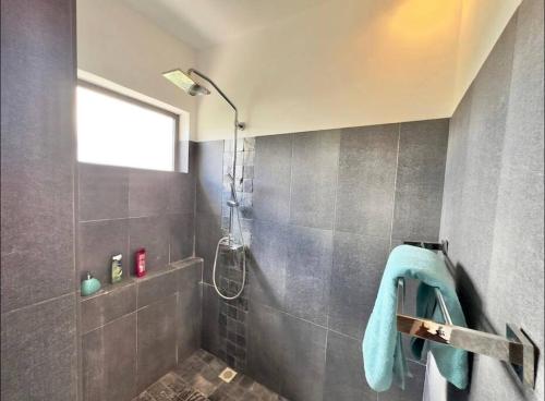 a bathroom with a shower with a blue towel at Seaview Sunset Apartment in Tamarin
