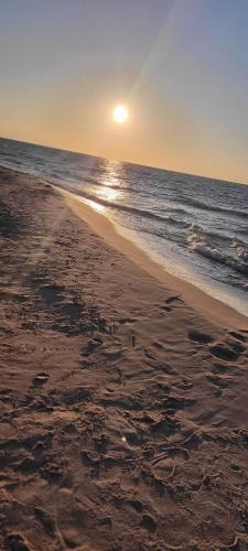 a beach with the sun rising over the ocean at Sunset Beach in Sarbinowo