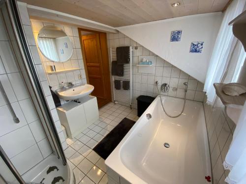 biała łazienka z umywalką i wanną w obiekcie Direkt am Hopfensee- Ferienwohnung w Füssen