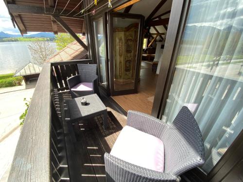 a balcony with chairs and a table and a door at Direkt am Hopfensee- Ferienwohnung in Füssen