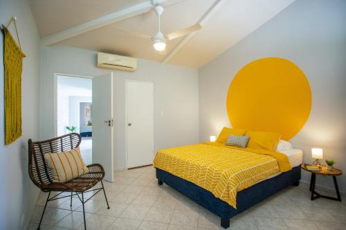 a bedroom with a yellow bed and a chair at Casa Monte Bello in Willemstad