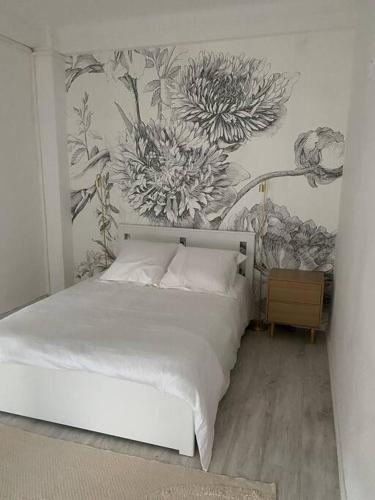 ein Schlafzimmer mit einem weißen Bett mit Blumen an der Wand in der Unterkunft Beautiful central beach apartment in Juan Les Pins in Antibes