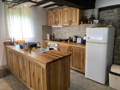 eine Küche mit Holzschränken und einem weißen Kühlschrank in der Unterkunft Къща за гости НОВЕ in Terziysko