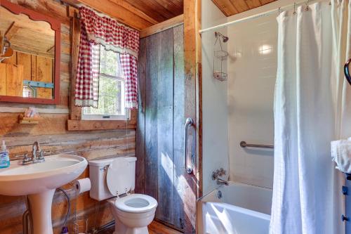 a bathroom with a toilet and a sink and a tub at Historic Log Cabin with Porch Near Patoka Lake! in Taswell