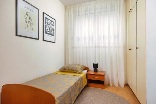 um pequeno quarto com uma cama e uma janela em NIVI Apartment em Split