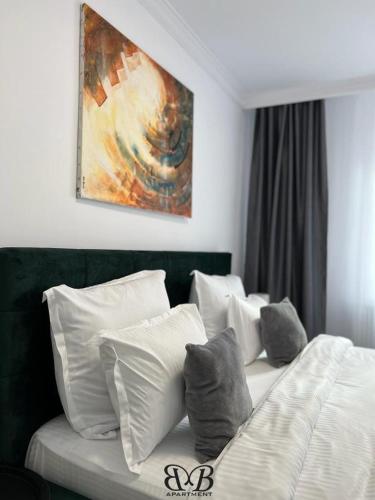 a bed with white pillows and a painting on the wall at B&B Apartment in Oţelu Roşu